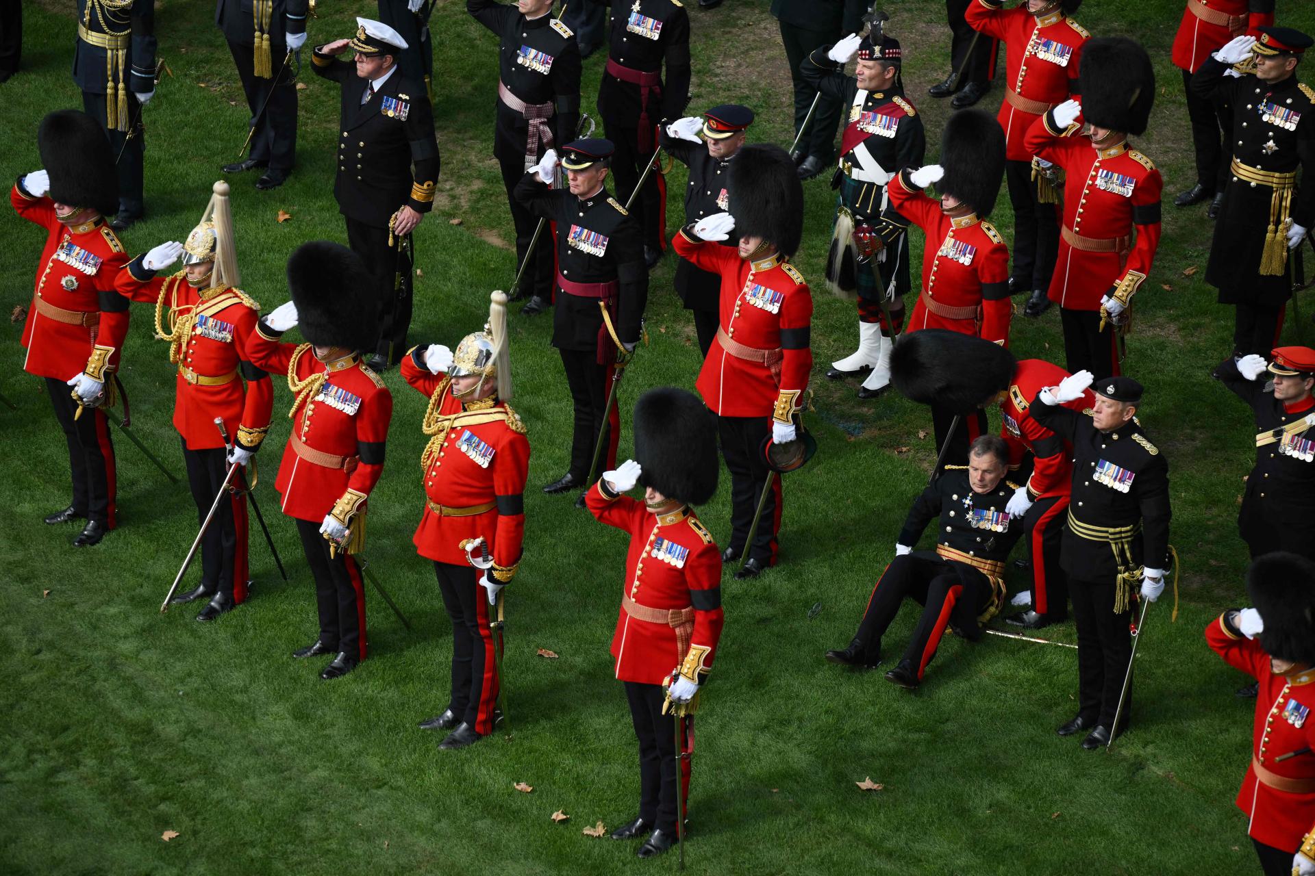 A guardsman helps a fallen comrade at Wellington Arch in London on September 19, 2022, after the State Funeral Service of Britain's Queen Elizabeth II. (Photo by Daniel LEAL / POOL / AFP)